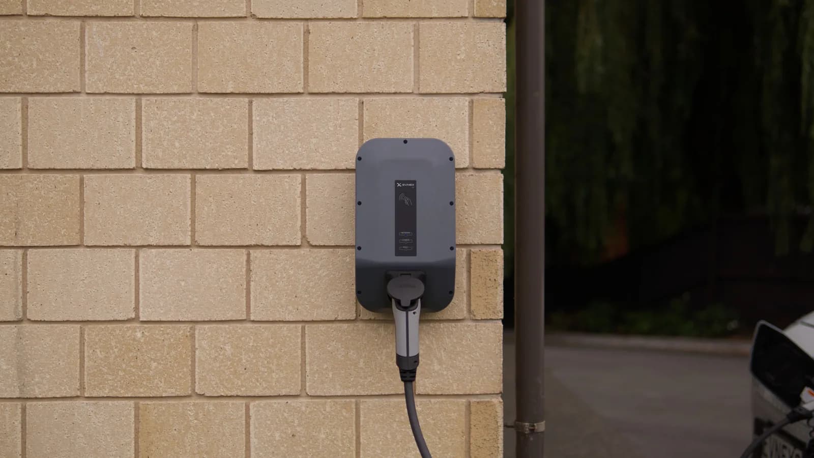 A wall-mounted electric vehicle charger on a brick wall