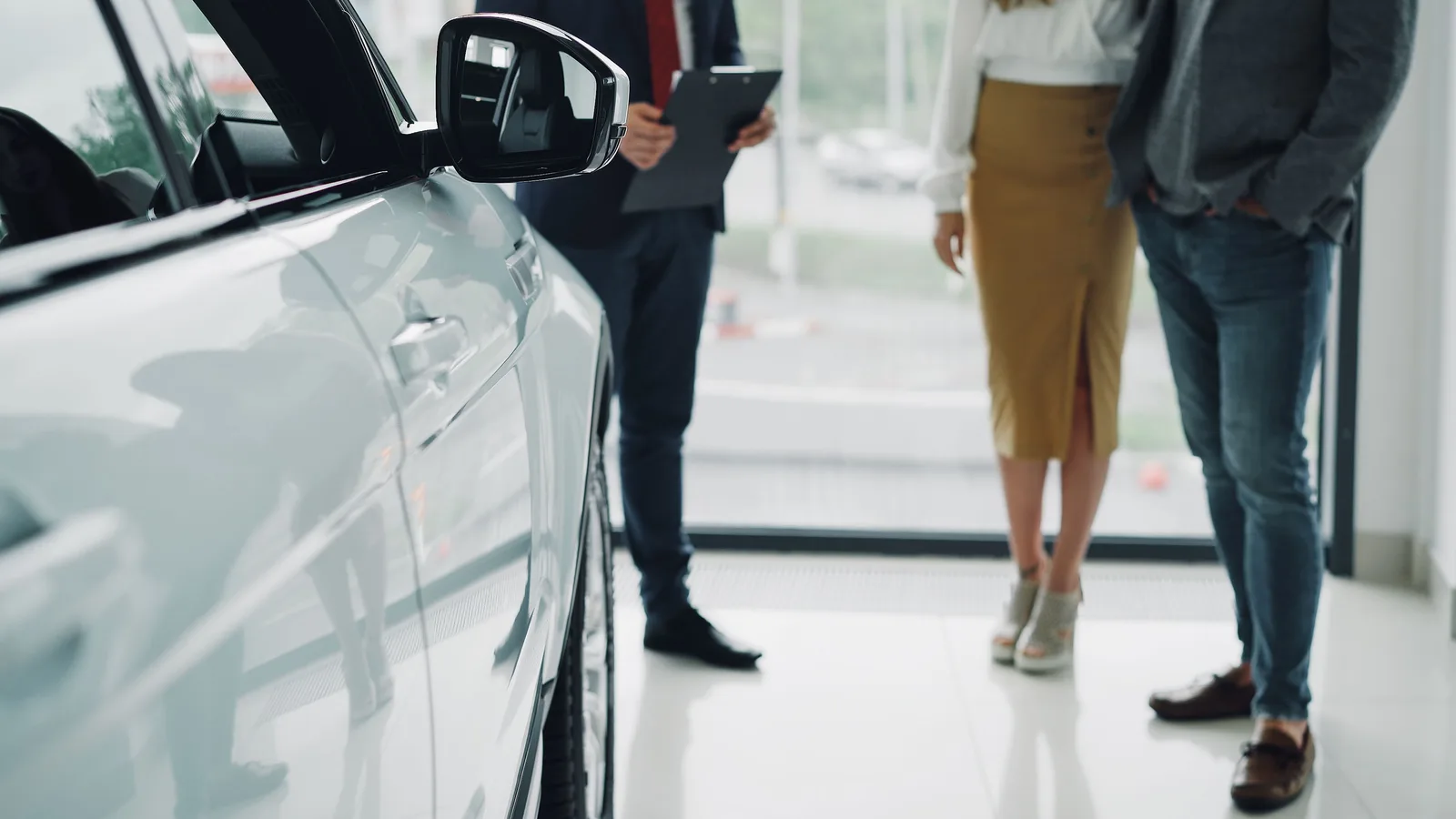 A couple discussing a car purchase with a salesperson in a dealership showroom